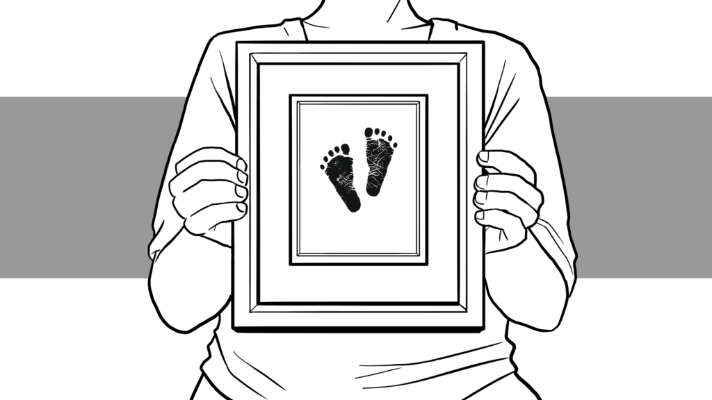 Parent holding a framed image of their child's footprints. 